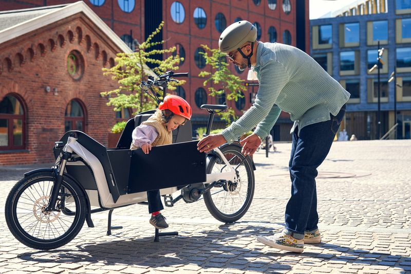 un pere de famille depose ses enfants a l'école a l'aide de son velo cargo