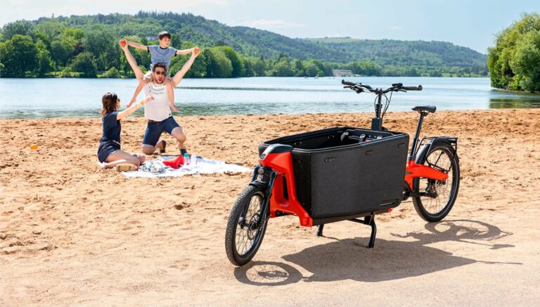 velo cargo electrique sur la plage avec la petite famille heureuse